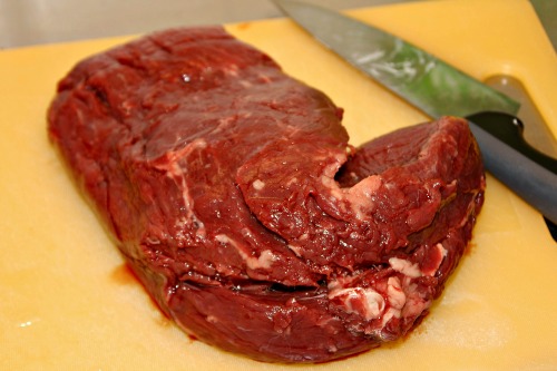 Raw beef on cutting board for homemade puppy food recipe Raw beef for homemade puppy food